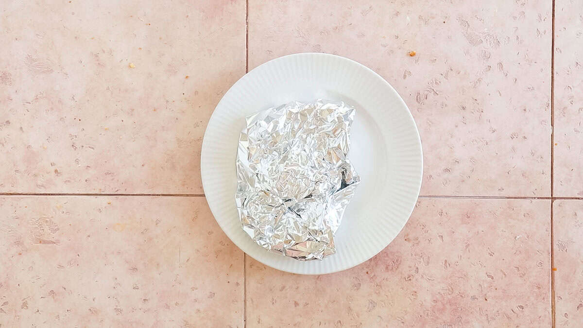 A bone in pork chop wrapped in foil after cooking it in the air fryer.