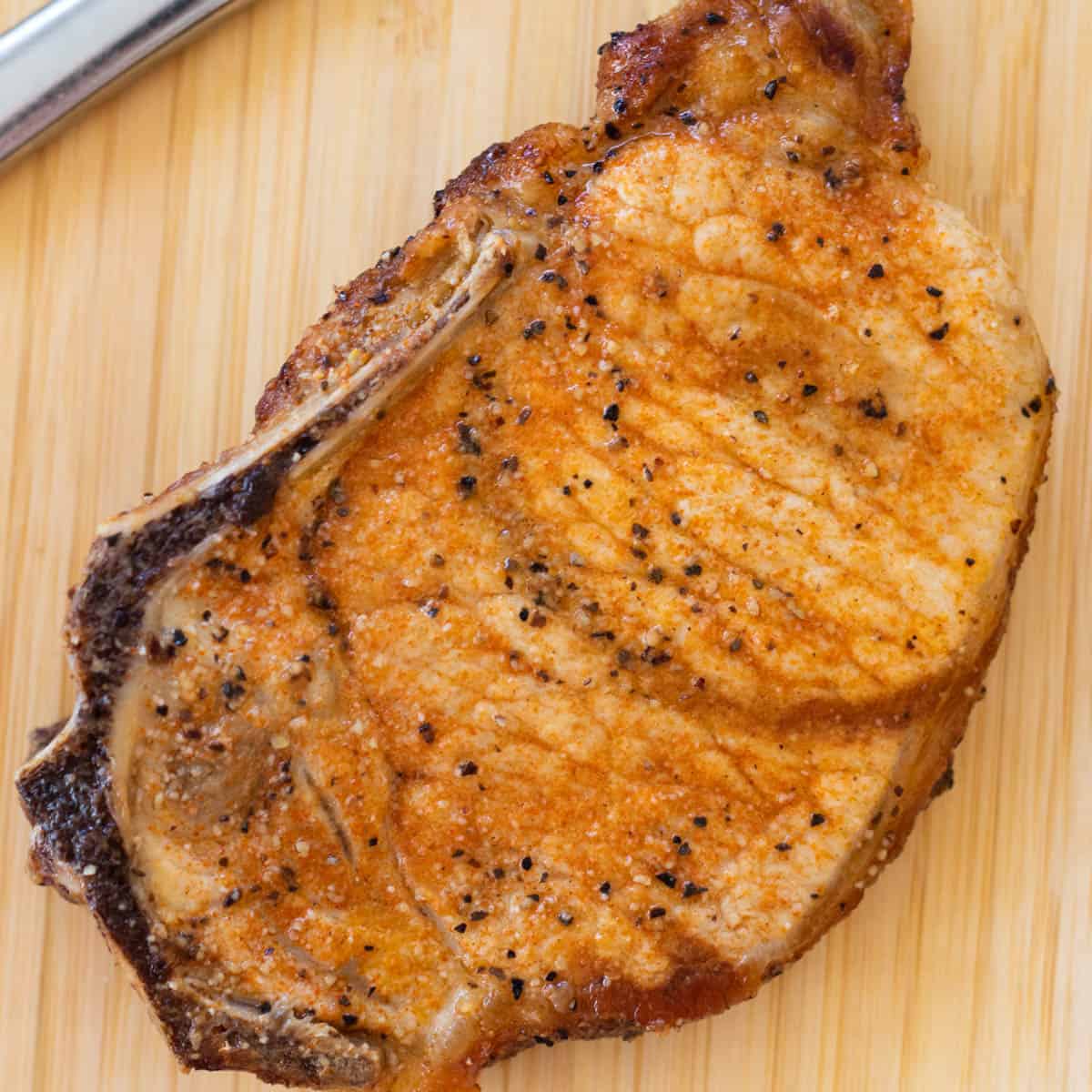 A pork chop on a small chopping board.