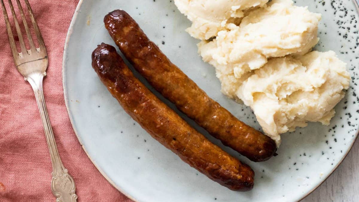 A plate with sausages and mashed potatoes.