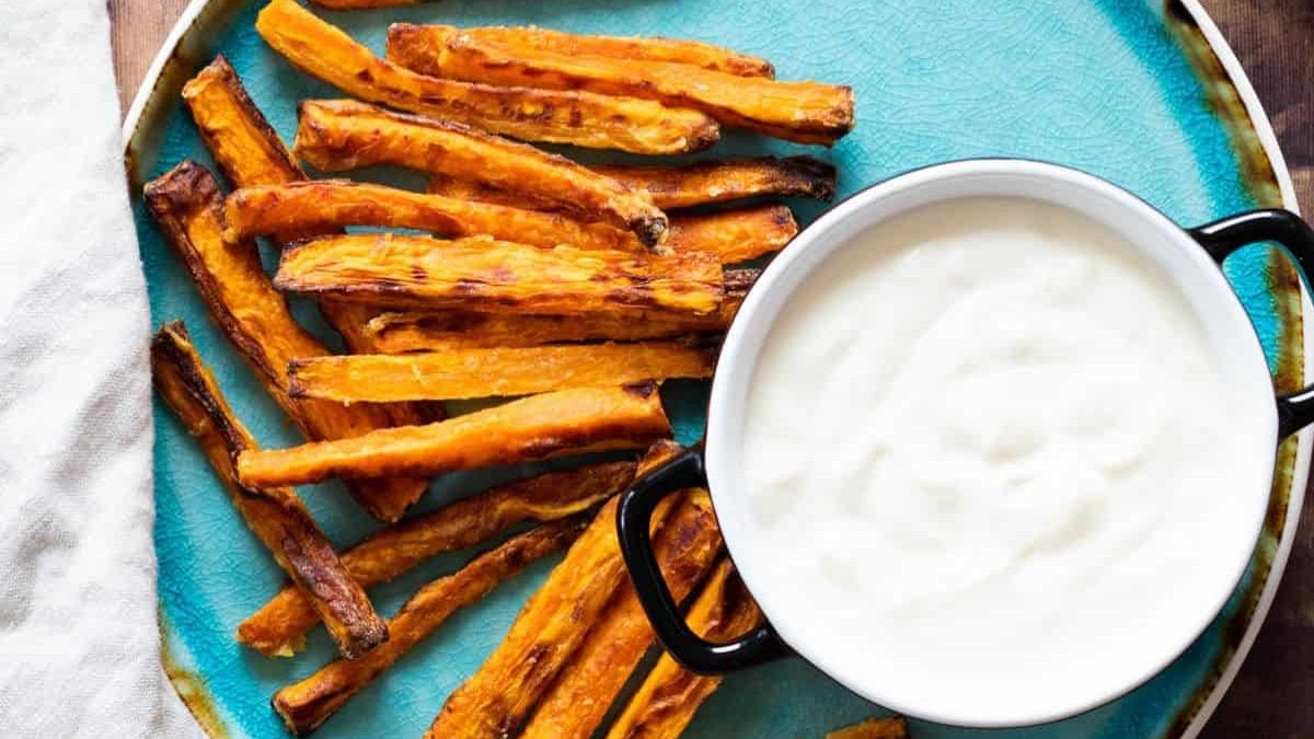 Carrot fries on a blue plate with a dip sauce.