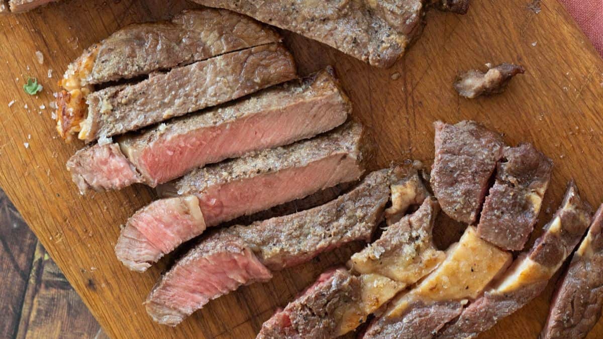 Sliced steak on a wooden chopping board.