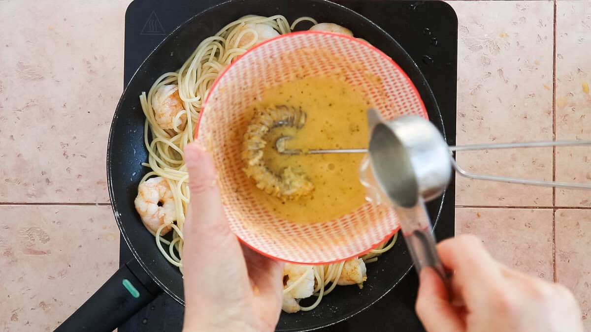 Adding pasta water to temper the eggs for a carbonara.