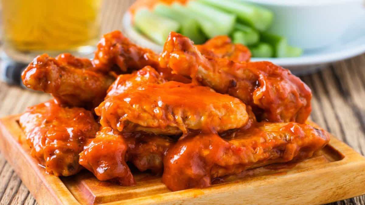 Buffalo chicken wings with cayenne pepper sauce served hot with celery sticks and carrot sticks with blue cheese dressing for dipping and beer