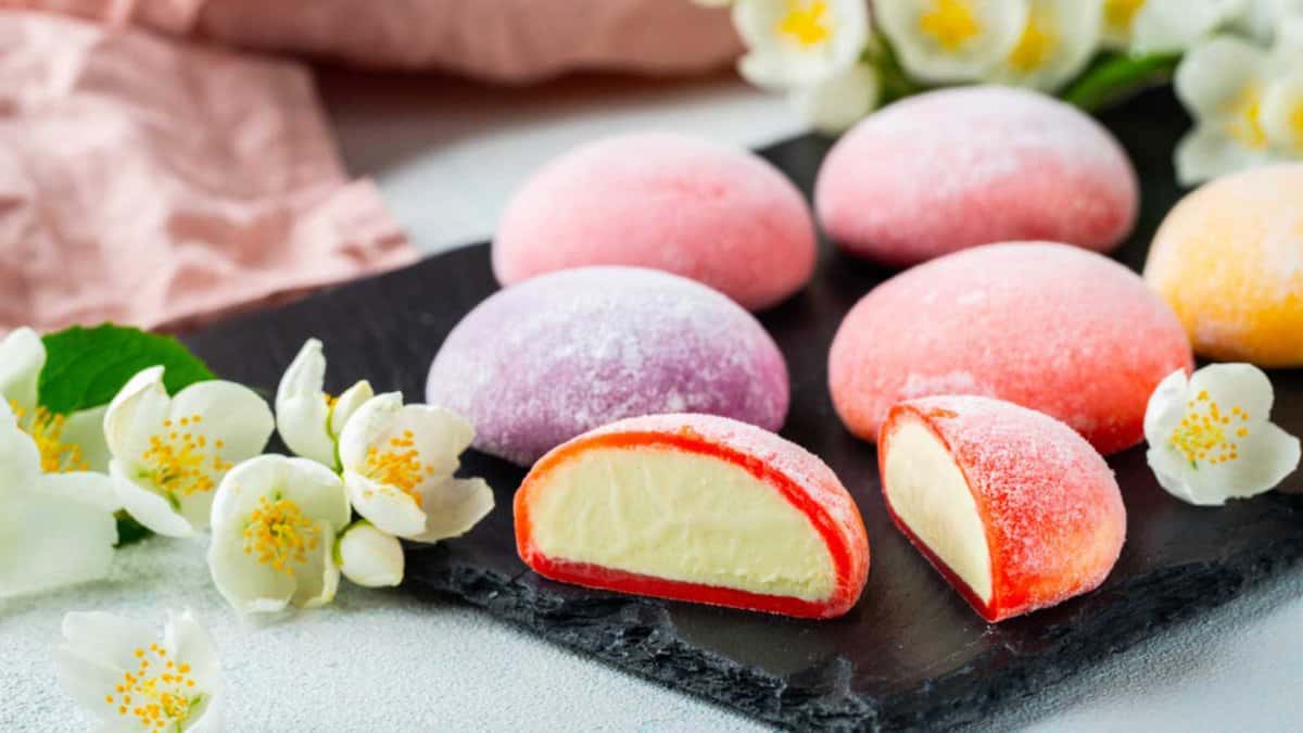 Multi-colored Japanese ice cream Mochi in rice dough and Jasmine flowers on a concrete blue background. Traditional Japanese dessert on a black slate
