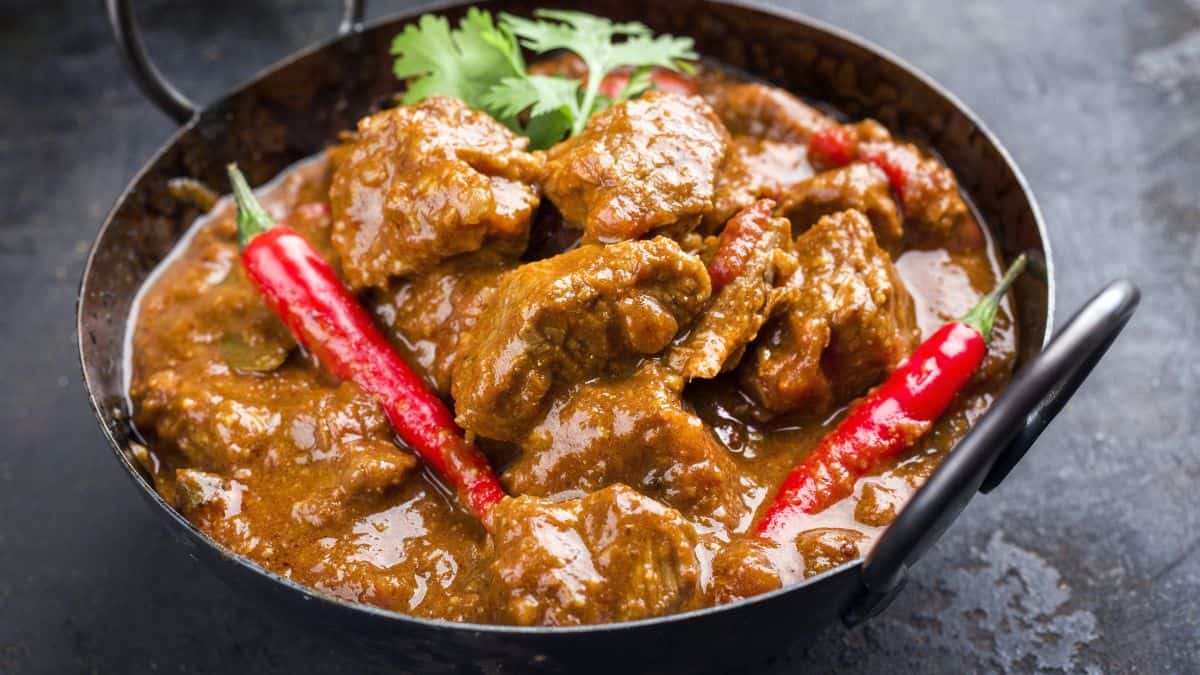 A bowl of curry topped with chilies.