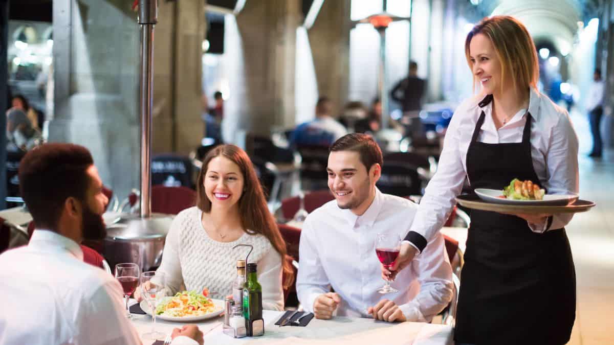 Three people at a table being served by a woman.