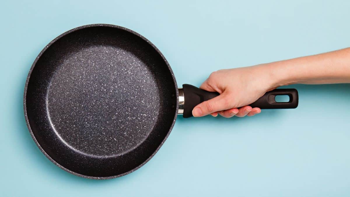 A hand holding a non stick pan.