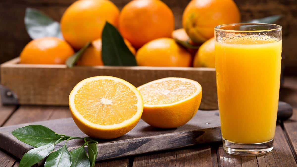 Half an orange next to a glass of orange juice.