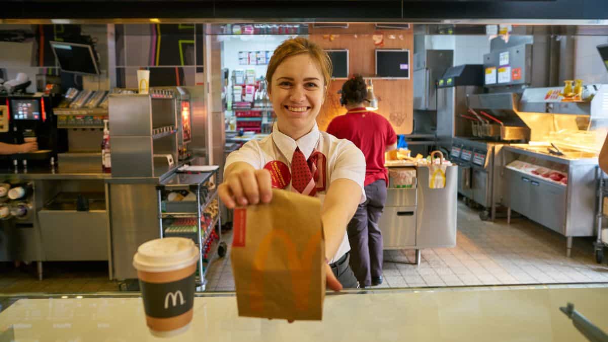 A cashier at McDonald's handing over a bag of food.