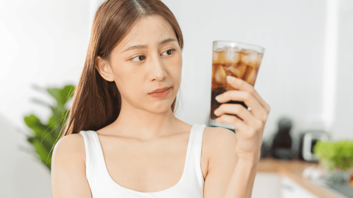 A woman looking at a glass of Coke.