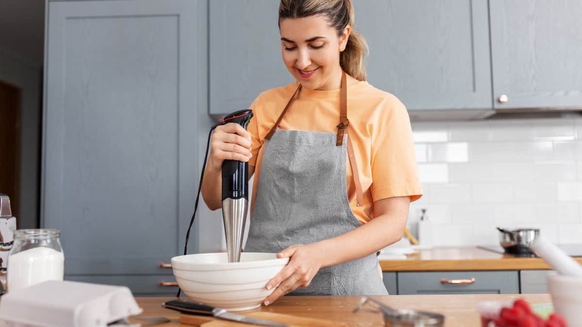 A woman using an immersion blender.