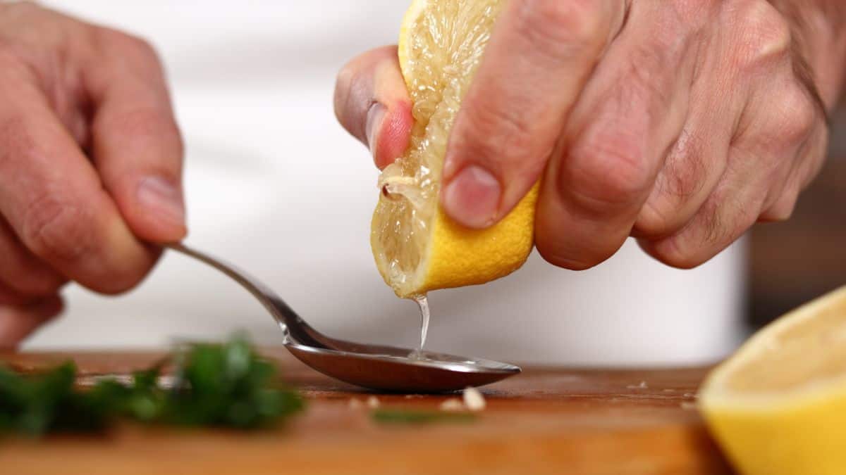A person squeezing lemon into a spoon.
