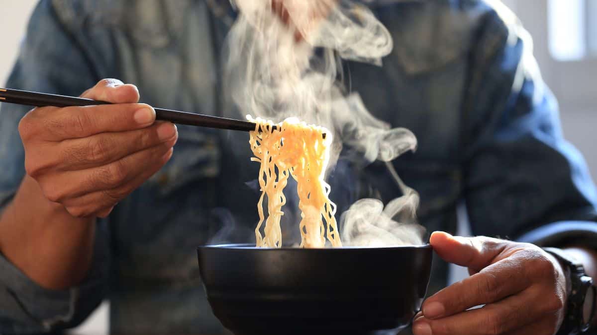 A person lifting ramen noodles from a bowl with chop sticks.