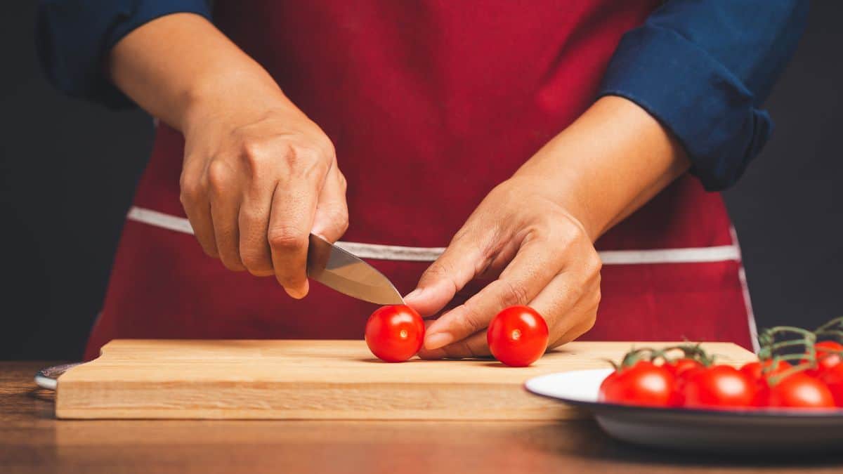 A woman slicing cherry tomatoes with a small knife.