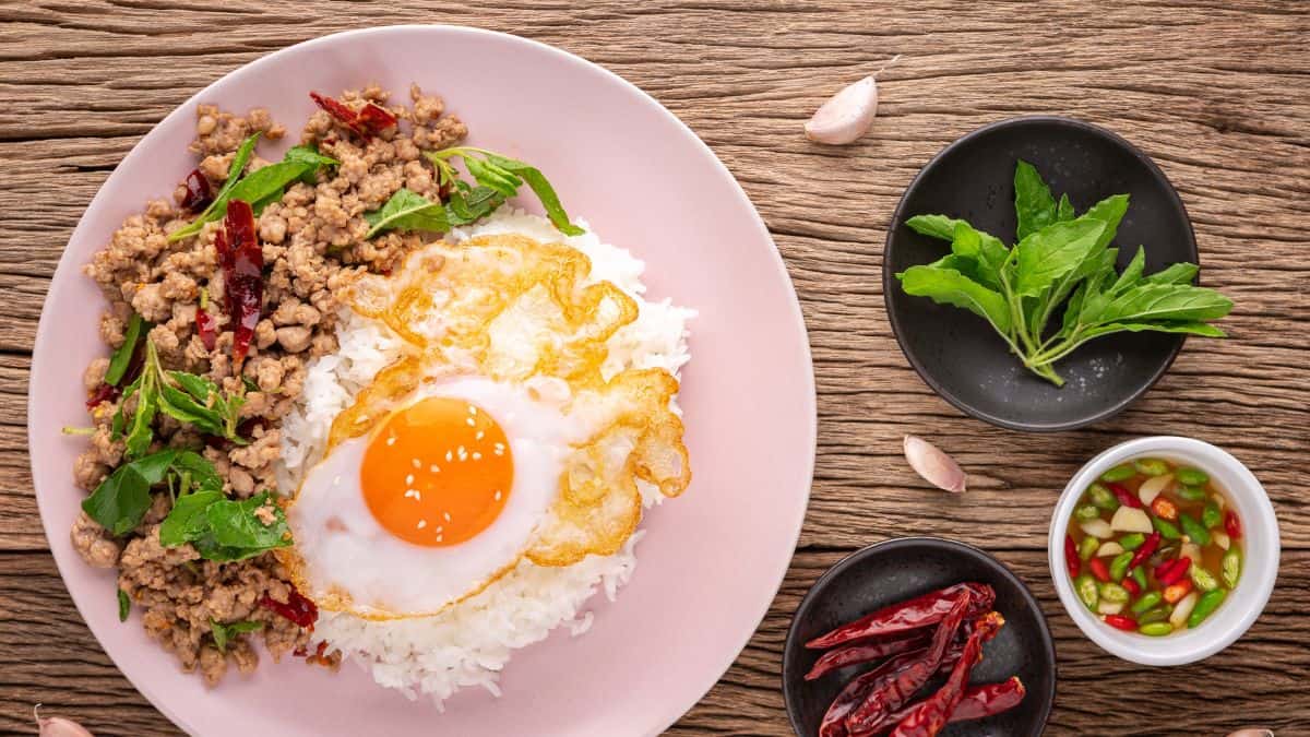 A plate with pad ka prao and rice served with a fried egg.