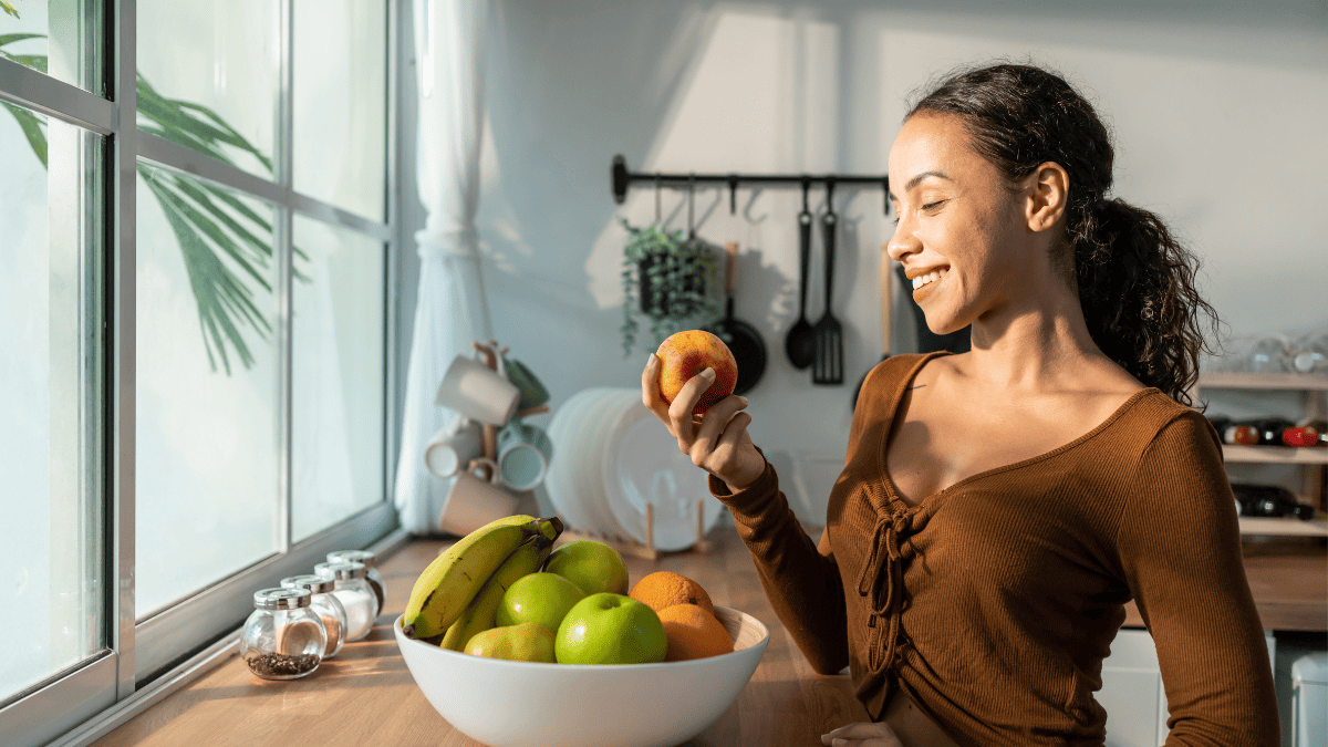 A latino woman holding an apple.