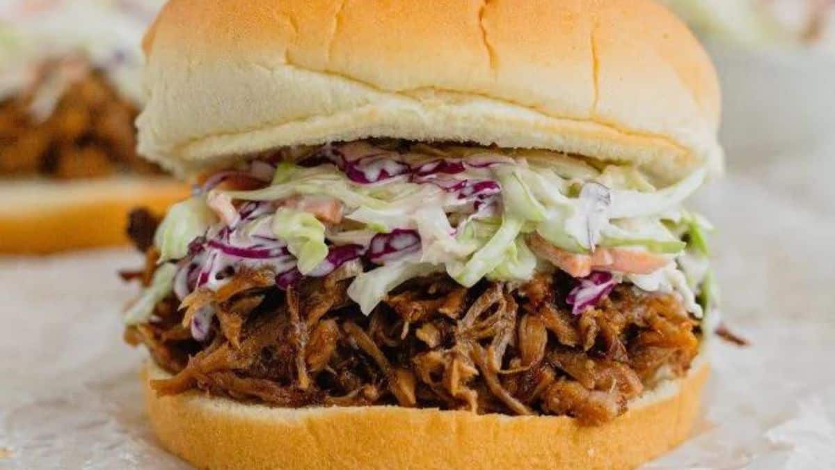 A burger topped with pulled pork and slaw.
