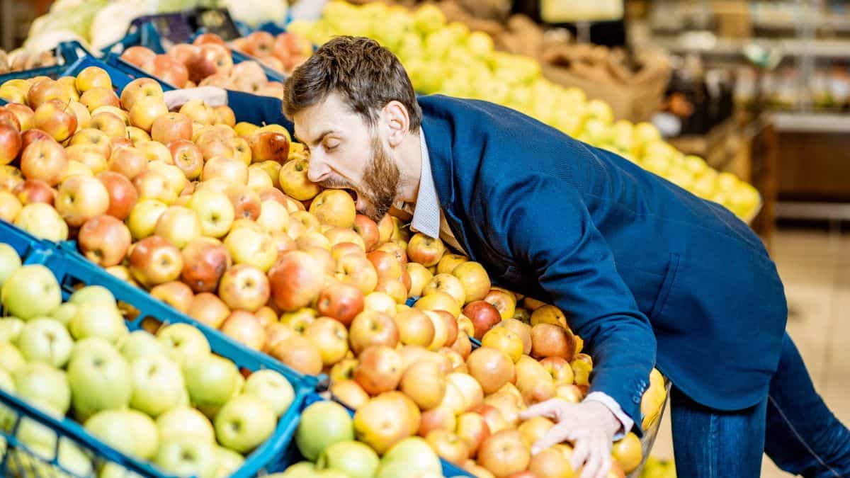A man biting into an apple in a pile of apples.