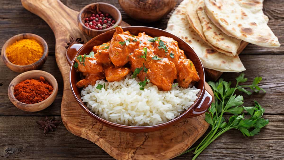 A plate with rice and chicken tikka masala.