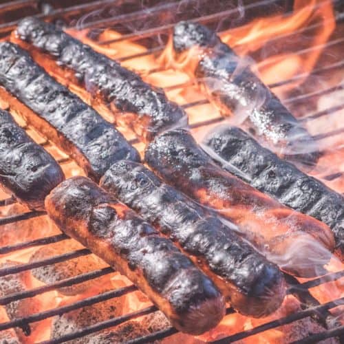Burned hot dogs on a grill.