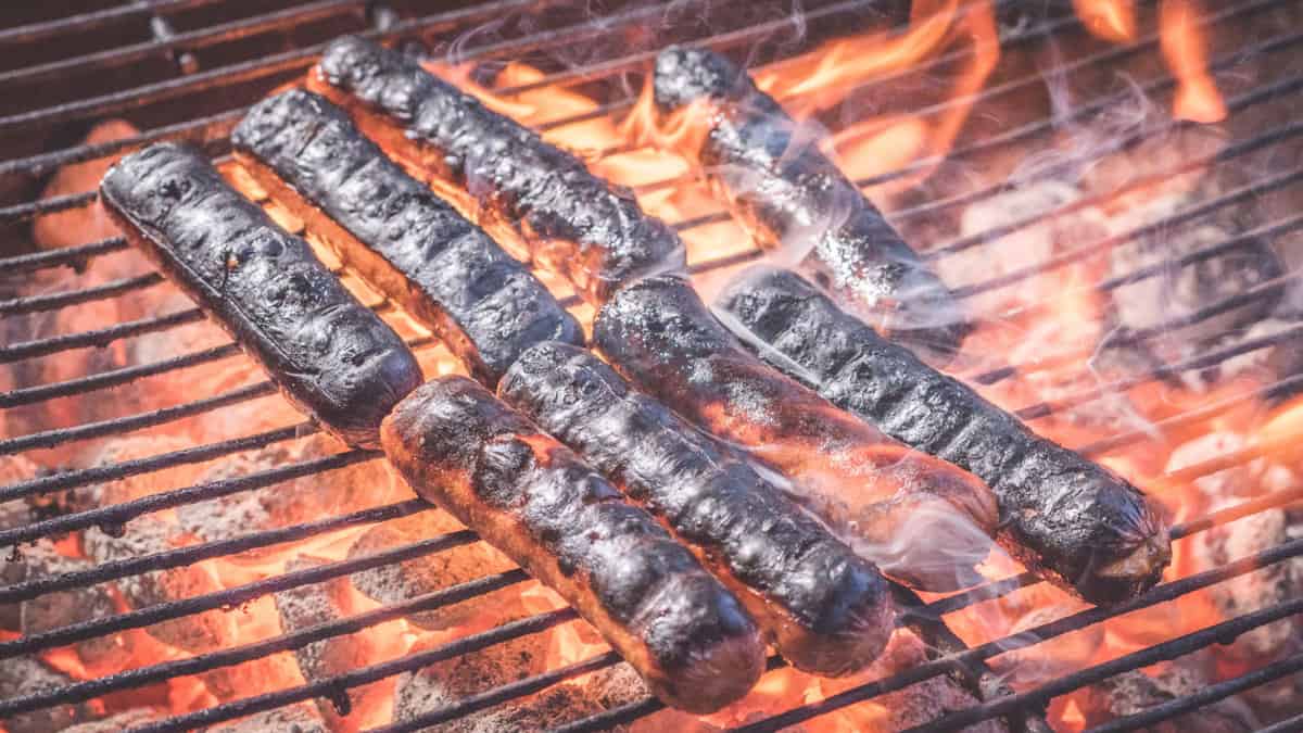 Burned hot dogs on a grill.