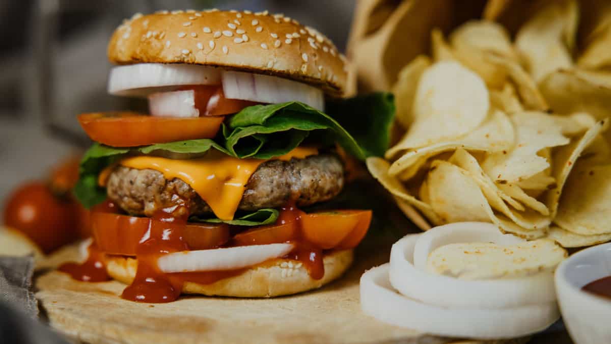 A burger next to some chips.