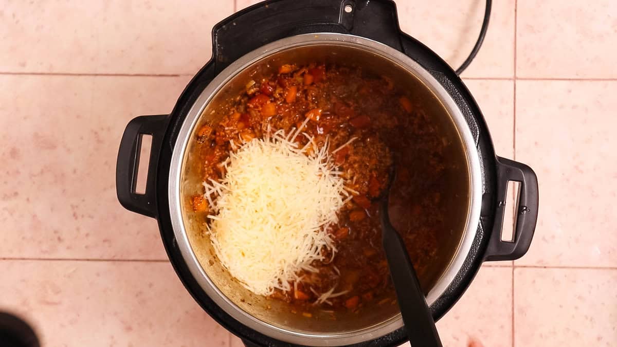 Adding parmesan cheese to instant pot bolognese after pressure cooking.