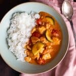 A bowl of thai salmon curry with rice.