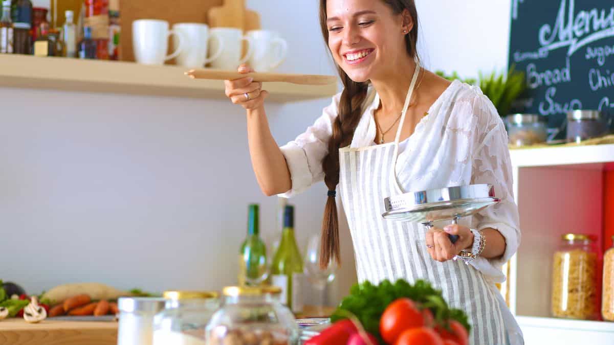 A smiling woman tasting food.