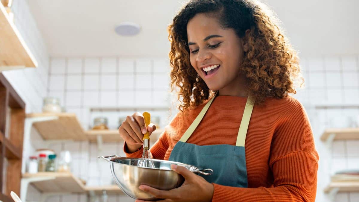 A smiling woman cooking.