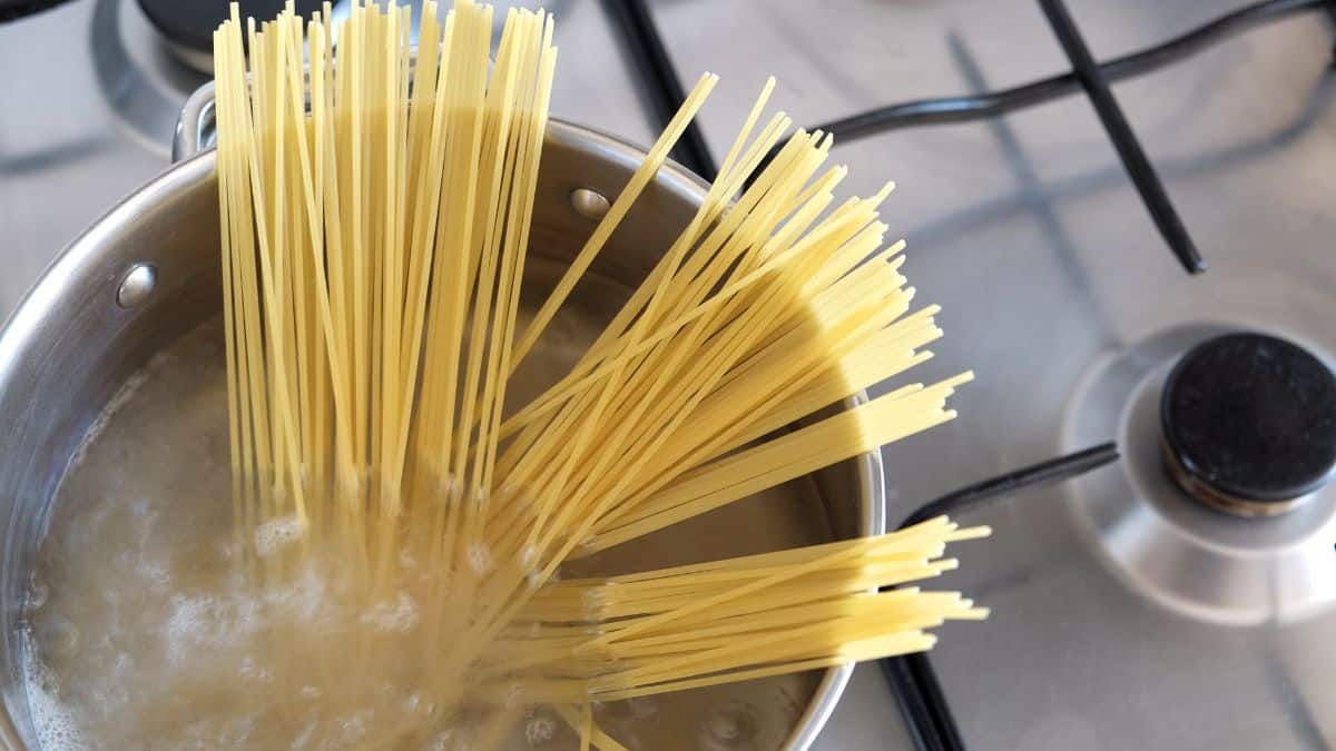 Uncooked spaghetti in a pot of water.