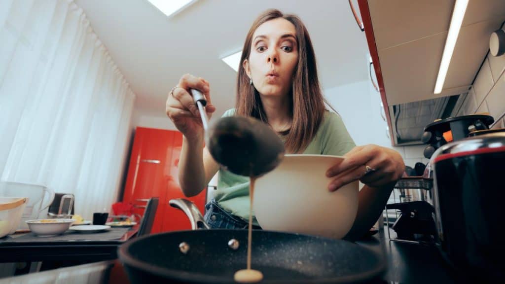 A woman stirring a pot in a cozy kitchen, her focus unwavering as steam rises from the stove.
