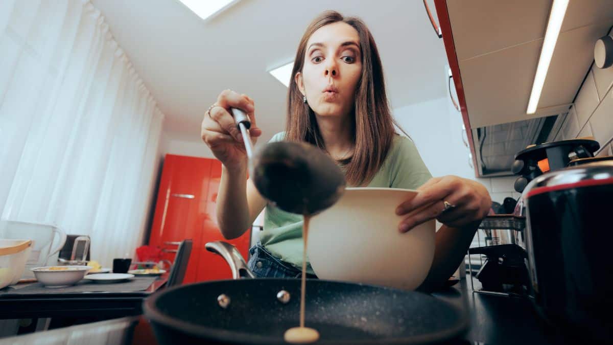 A woman pouring pancake batter in a pan.