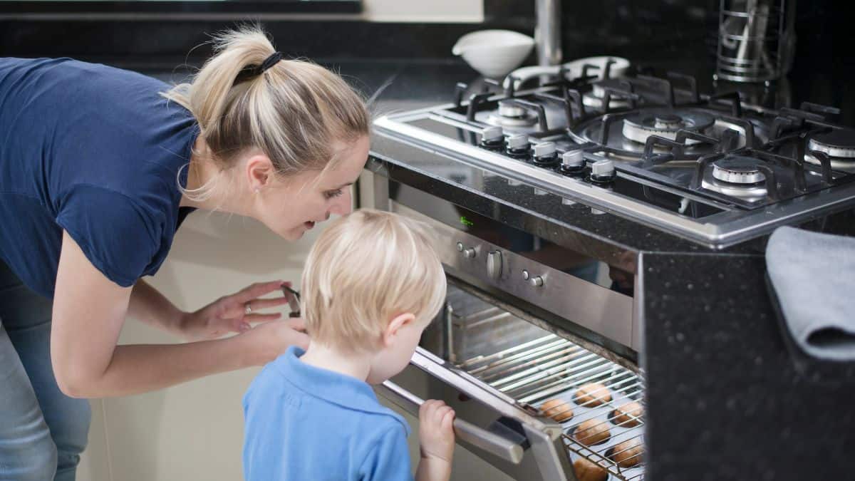 A woman and a child checking on things in the oven.