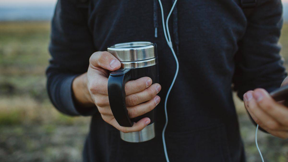 A person holding a traveling mug.