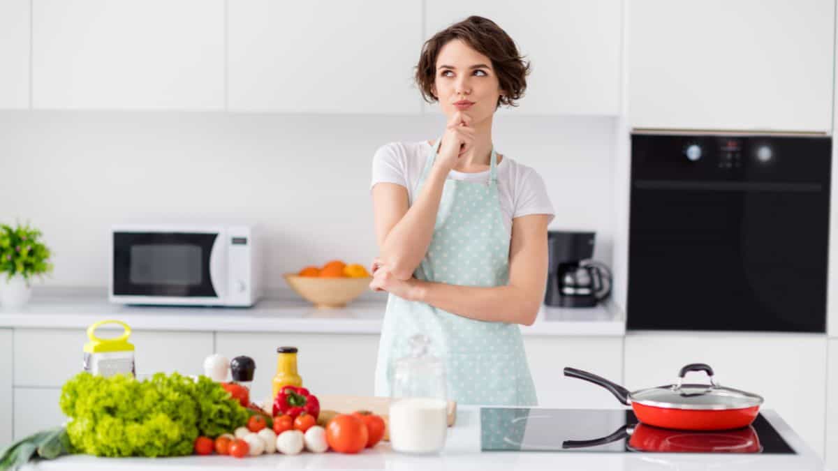 A woman thinking in a kitchen.