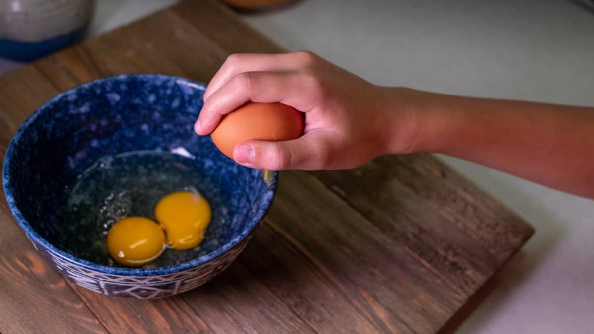 Cracking an egg against a bowl.