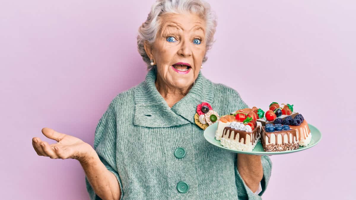 An older woman holding a plate with cakes.