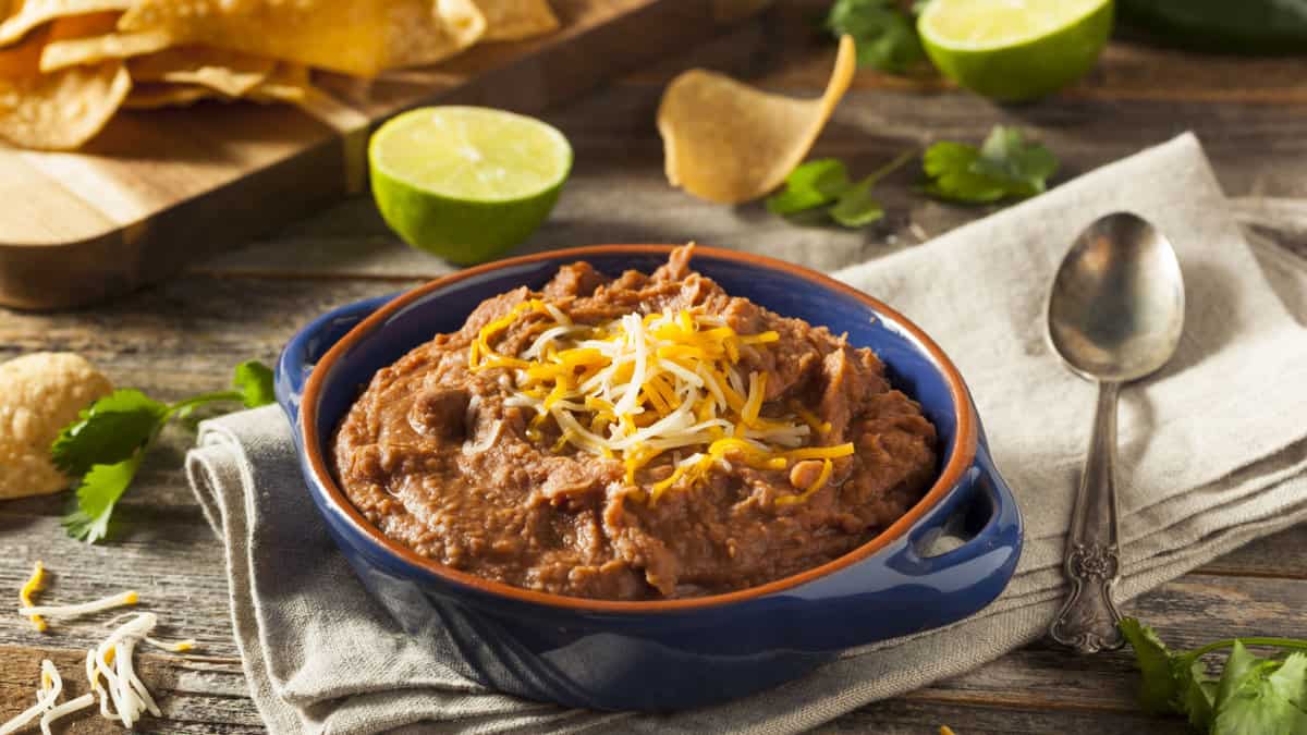 A bowl of refried beans topped with cheese.