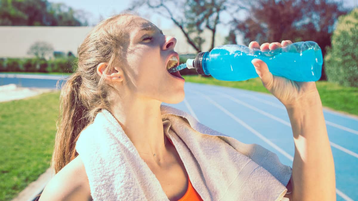 A woman drinking sports drink.