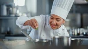 A female chef seasoning food.