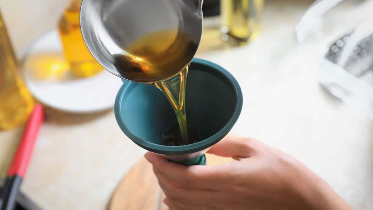 A person pouring liquid thorugh a funnel.