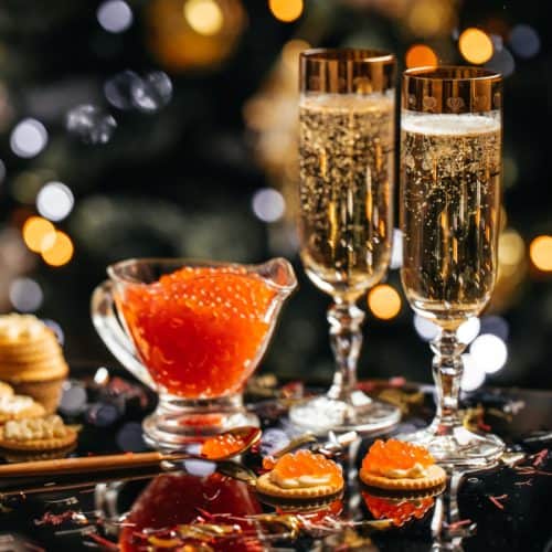 Two glasses of champagne next to caviar.