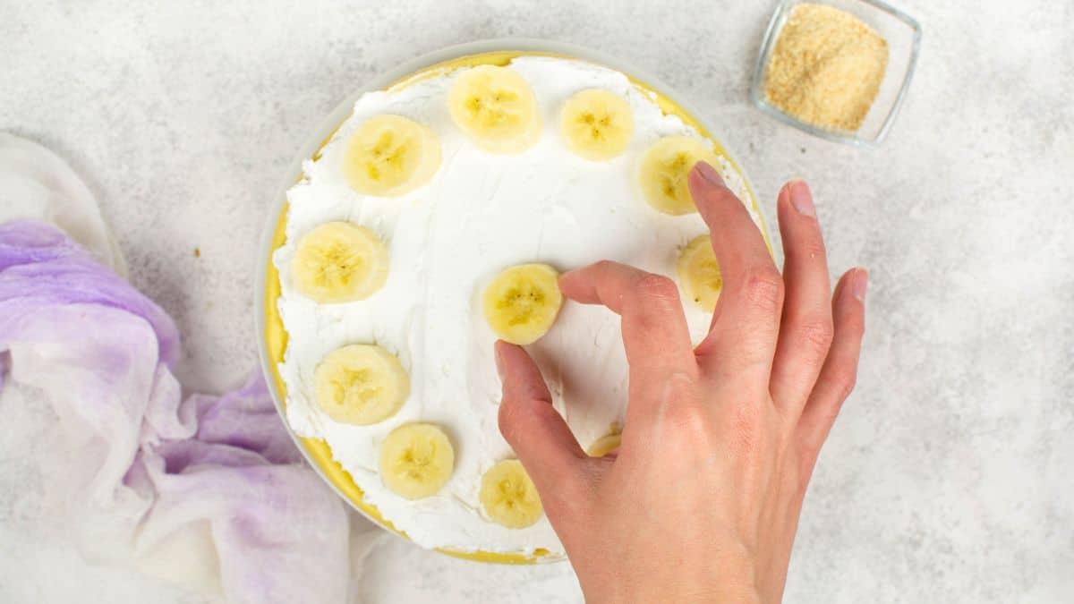 Placing bananas on a cheesecake.