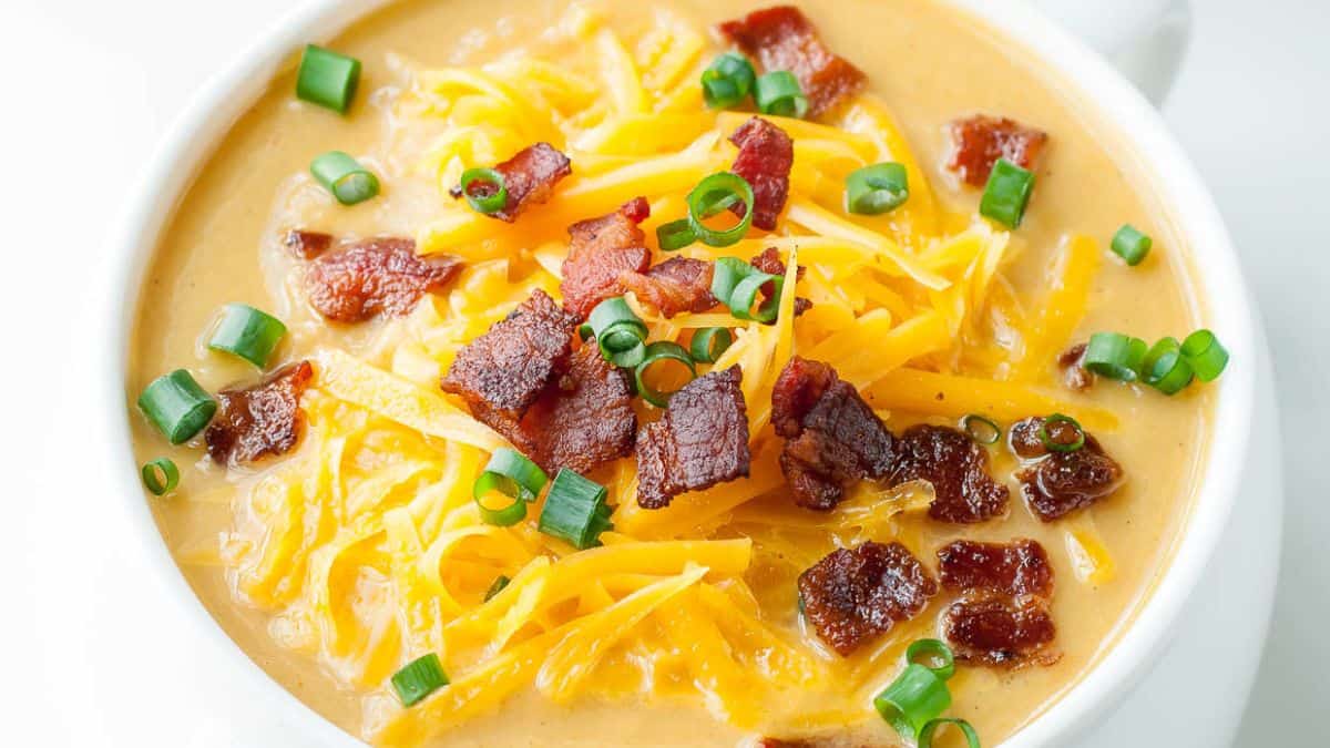 A bowl of soup topped with cheese and bacon.