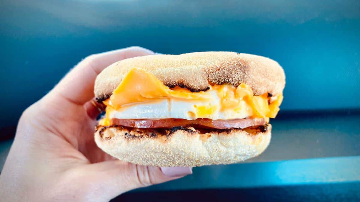 A hand holding a breakfast sandwich.