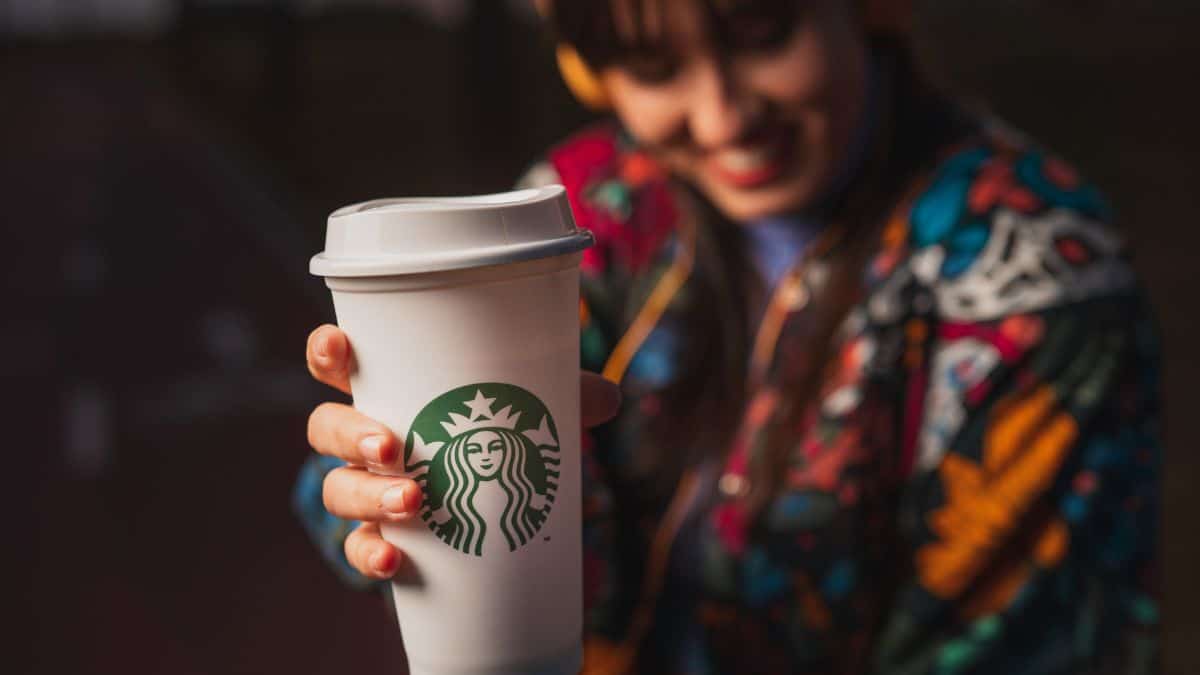 A woman holding a Starbucks to-go cup.