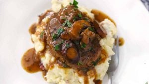 A plate with mashed potatoes and salisbury steak.