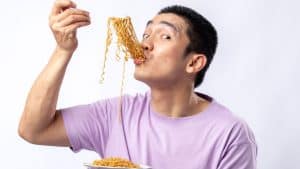 An Asian man eating noodles.
