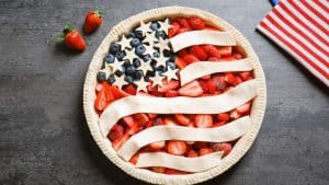 A pie with blueberries and strawberries made to look like an American flag, before baking.